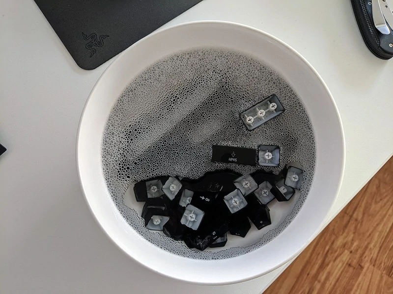 keycaps soaking in a bowl of soapy water